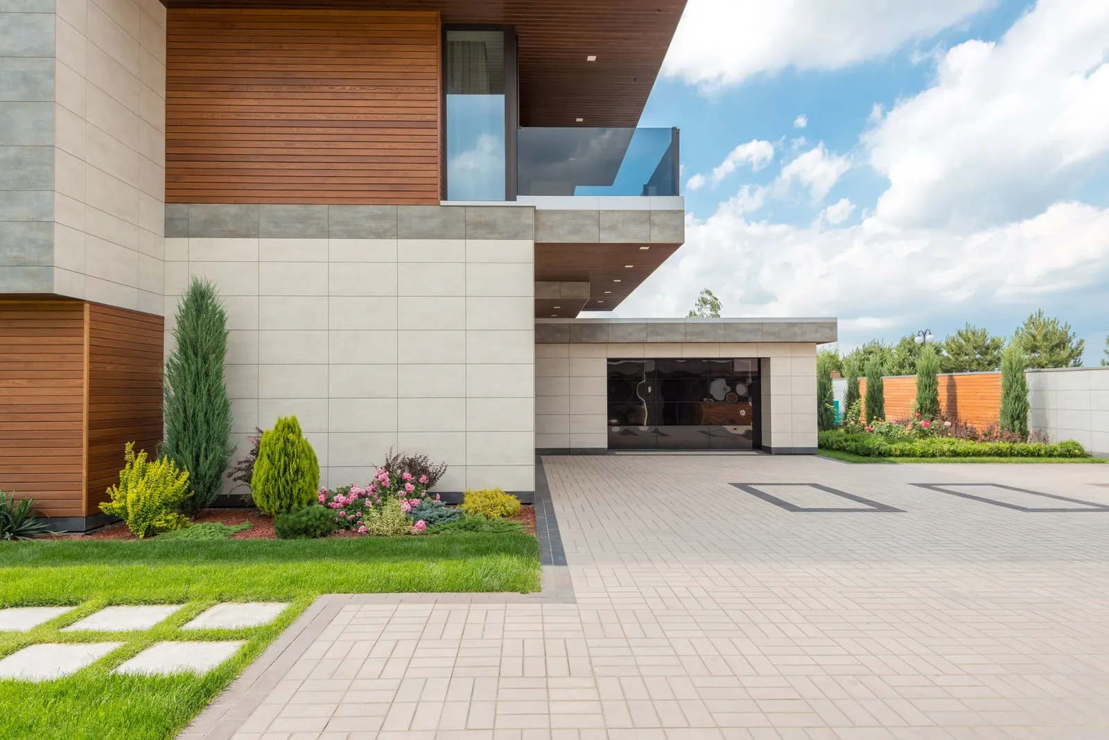 A modern house with a smooth, light-coloured driveway leading up to the garage